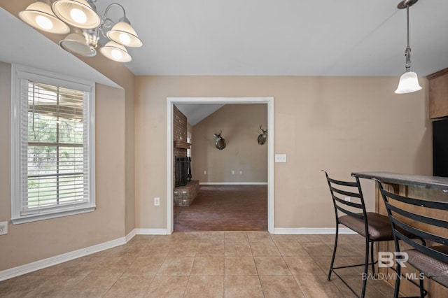 dining space featuring a fireplace, light carpet, light tile patterned floors, a chandelier, and baseboards