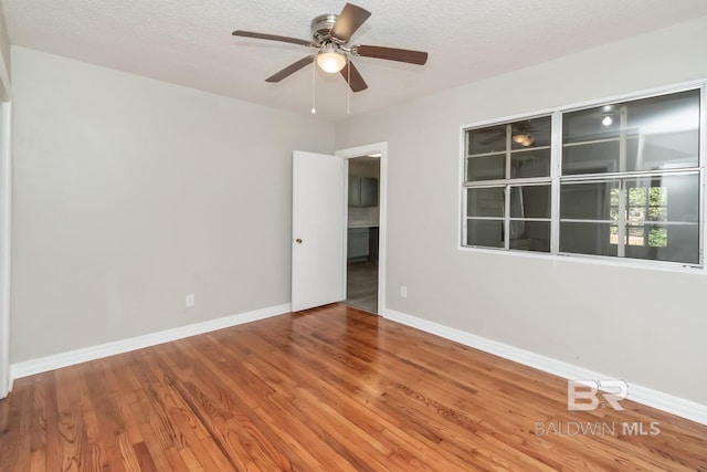 unfurnished room featuring ceiling fan, a textured ceiling, baseboards, and wood finished floors