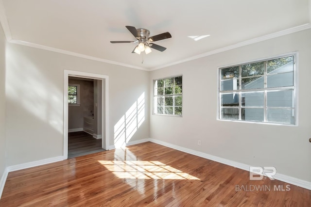 unfurnished room with a ceiling fan, crown molding, baseboards, and wood finished floors