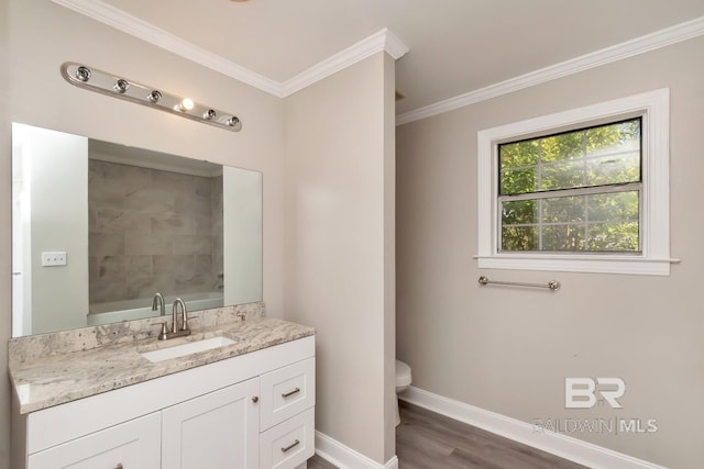 bathroom with baseboards, toilet, wood finished floors, crown molding, and vanity