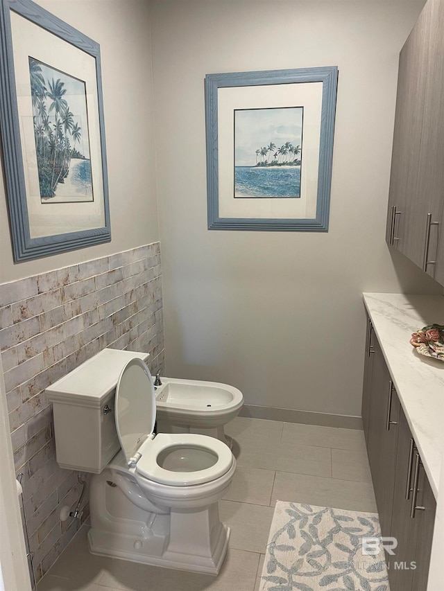 bathroom with vanity, toilet, tile patterned floors, and a bidet