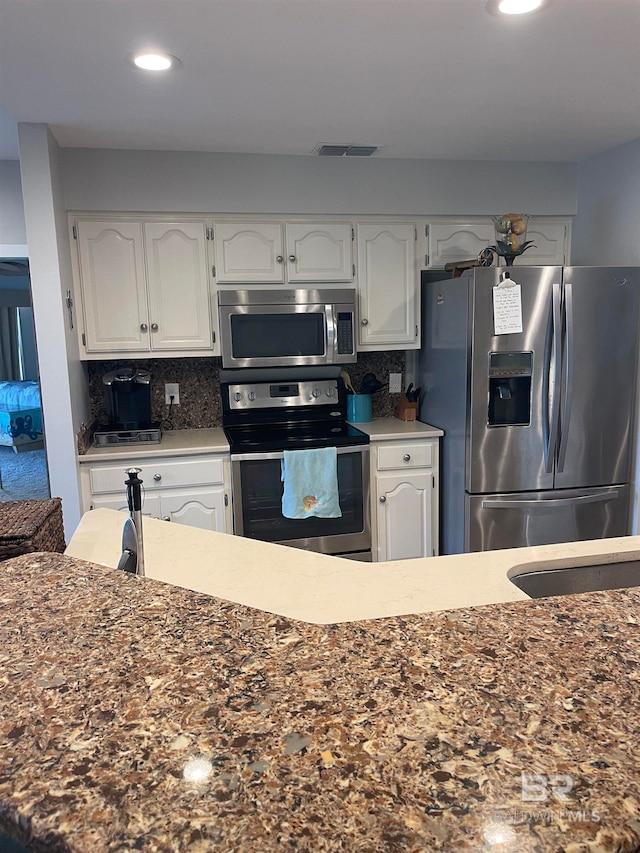 kitchen with white cabinetry, stainless steel appliances, and backsplash