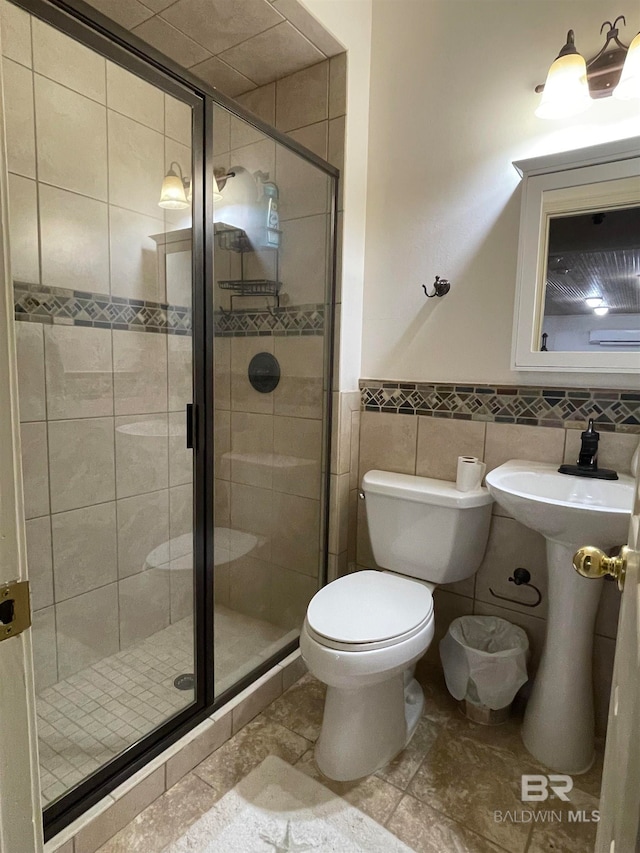 bathroom with toilet, an enclosed shower, and tile walls