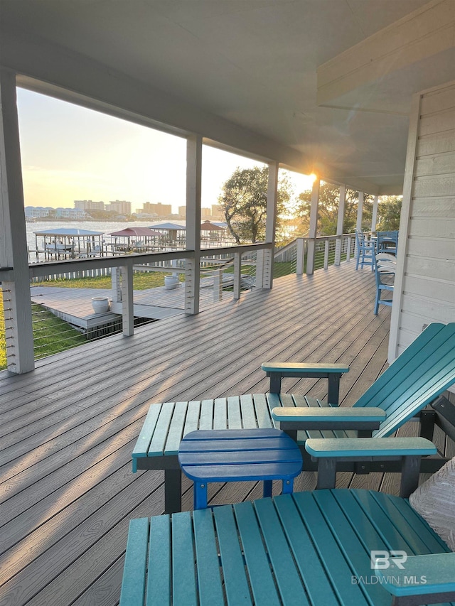 deck at dusk featuring a water view