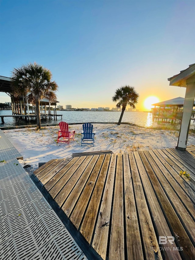 deck at dusk featuring a water view