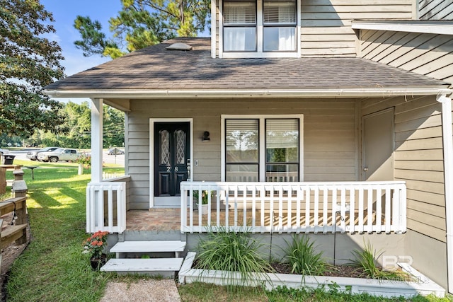 view of exterior entry with a lawn and covered porch