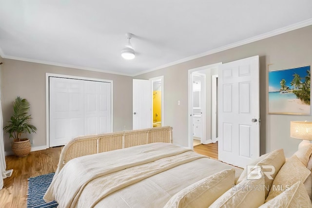 bedroom with hardwood / wood-style flooring, ornamental molding, connected bathroom, and a closet