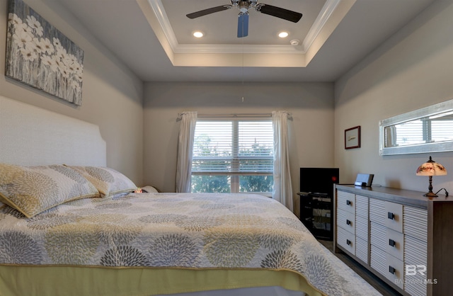 bedroom with ceiling fan, ornamental molding, a tray ceiling, and multiple windows