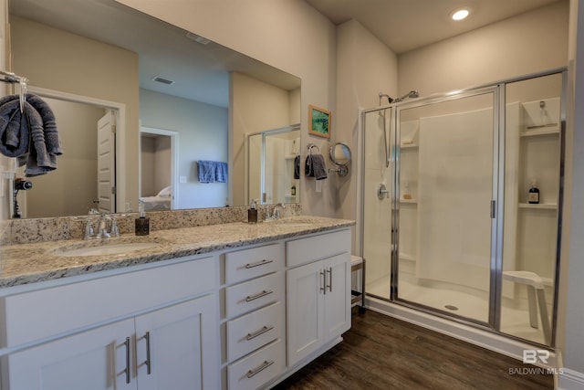 bathroom with hardwood / wood-style floors, vanity, and a shower with door