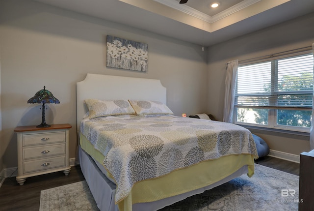 bedroom with dark hardwood / wood-style floors, a raised ceiling, and crown molding