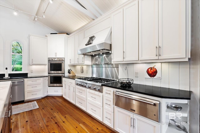 kitchen featuring stainless steel appliances, vaulted ceiling, white cabinets, and dark hardwood / wood-style flooring