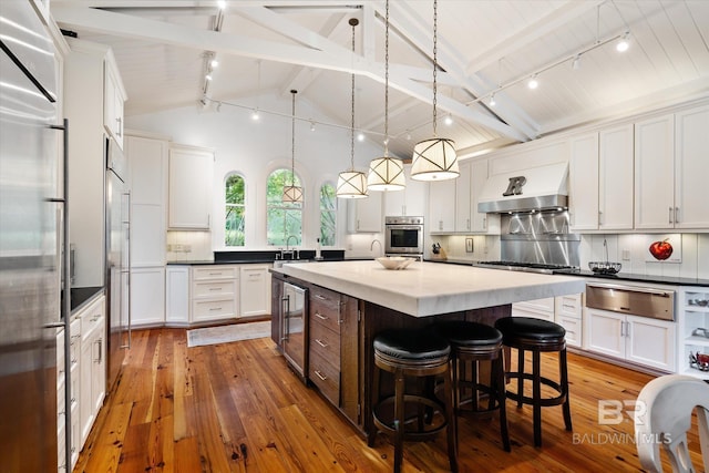 kitchen featuring decorative light fixtures, beverage cooler, decorative backsplash, custom exhaust hood, and a center island