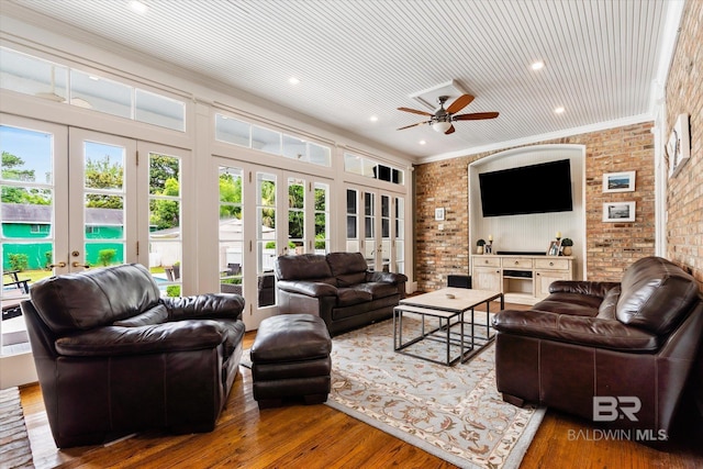 living room featuring crown molding, hardwood / wood-style flooring, ceiling fan, brick wall, and french doors