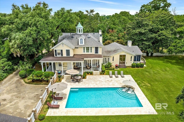 back of house featuring a fenced in pool, a lawn, an outdoor living space with a fire pit, and a patio