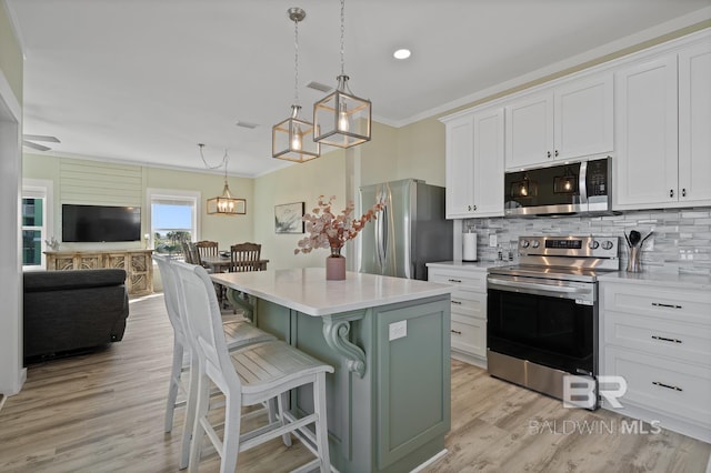 kitchen featuring appliances with stainless steel finishes, white cabinets, a kitchen island, a breakfast bar area, and light hardwood / wood-style flooring