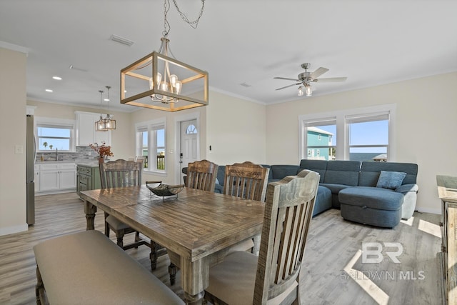 dining room featuring sink, ceiling fan with notable chandelier, crown molding, and light hardwood / wood-style floors