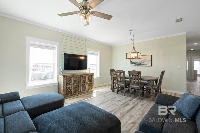 living room featuring ceiling fan with notable chandelier, light hardwood / wood-style floors, and ornamental molding