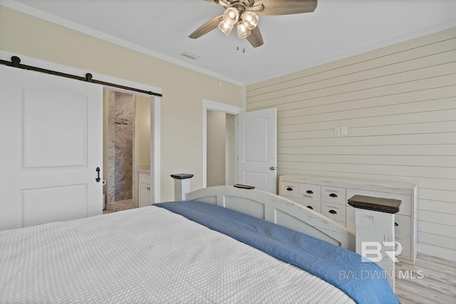 unfurnished bedroom with a barn door, wood walls, ceiling fan, ornamental molding, and hardwood / wood-style floors