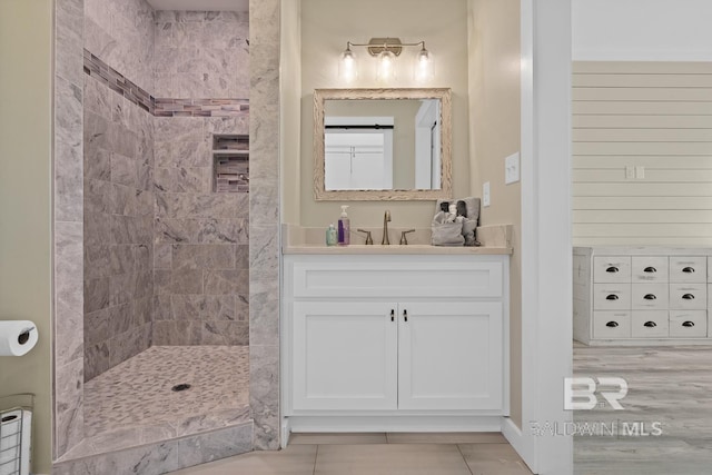 bathroom with tile patterned flooring, vanity, and tiled shower