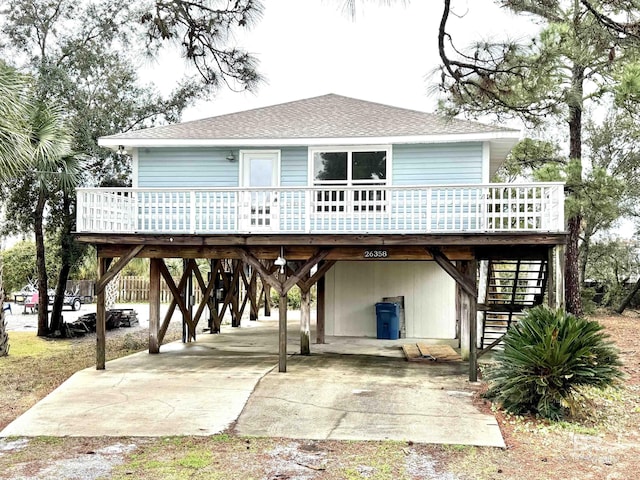 back of property featuring covered porch, a carport, stairway, and roof with shingles