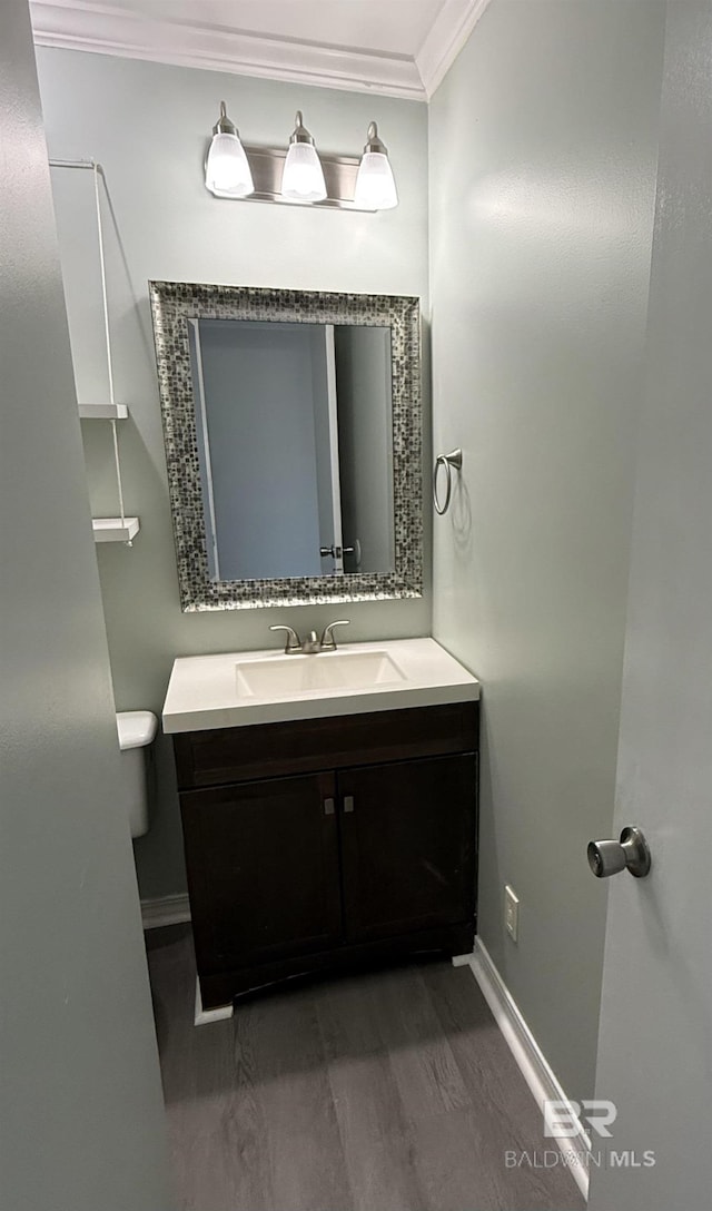 half bath with ornamental molding, vanity, and baseboards