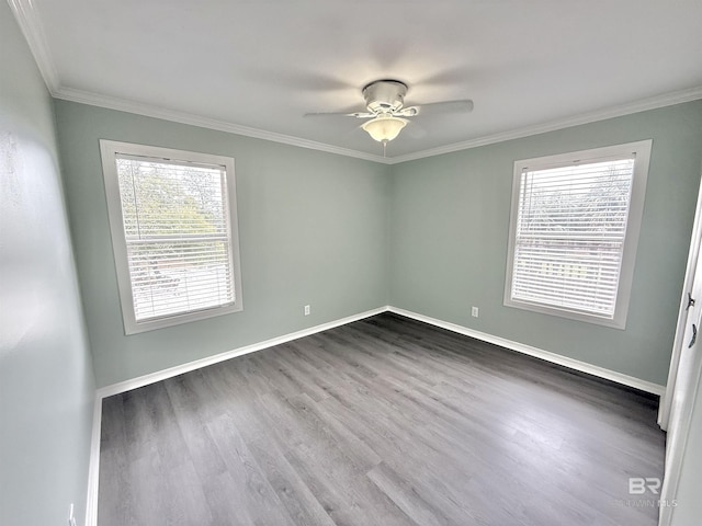 spare room with dark wood-style floors, baseboards, ornamental molding, and a ceiling fan