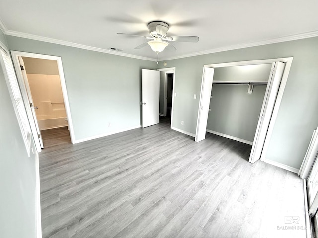 unfurnished bedroom with baseboards, visible vents, ornamental molding, wood finished floors, and a closet