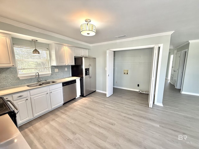 kitchen with a sink, light wood-style floors, light countertops, appliances with stainless steel finishes, and tasteful backsplash