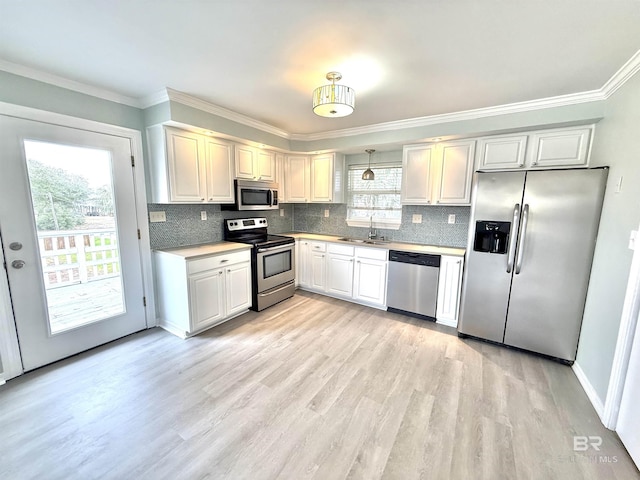 kitchen featuring appliances with stainless steel finishes, a wealth of natural light, light wood-type flooring, and a sink