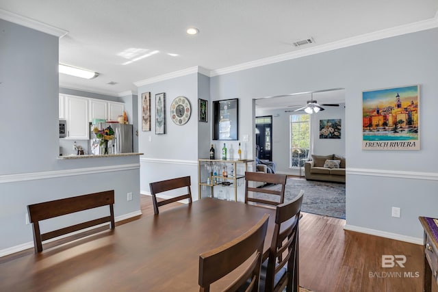 dining area featuring visible vents, ceiling fan, baseboards, ornamental molding, and wood finished floors