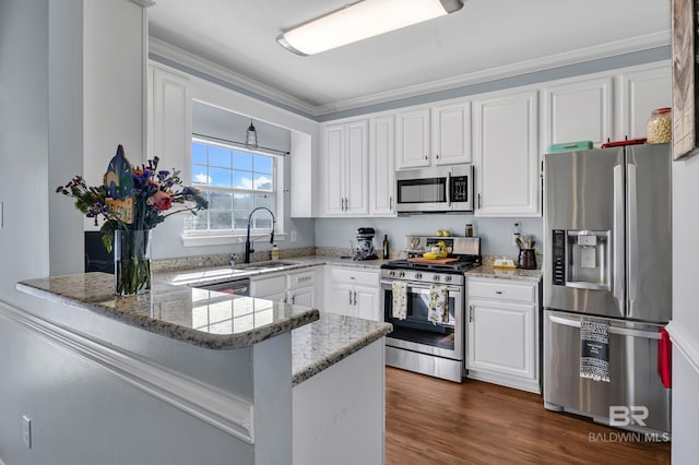 kitchen featuring light stone countertops, appliances with stainless steel finishes, a peninsula, white cabinetry, and a sink