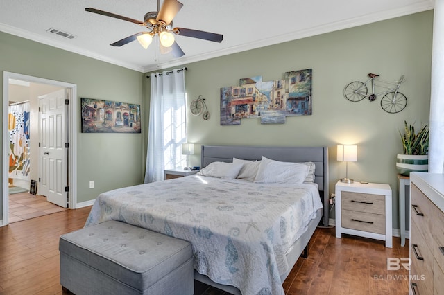 bedroom with dark wood finished floors, visible vents, baseboards, and ornamental molding