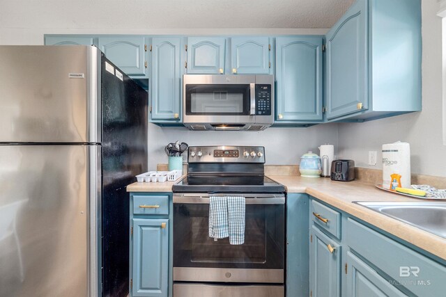 kitchen featuring blue cabinets, a textured ceiling, and appliances with stainless steel finishes