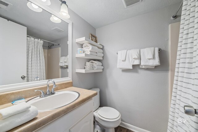 bathroom with a textured ceiling, vanity, toilet, and a shower with curtain