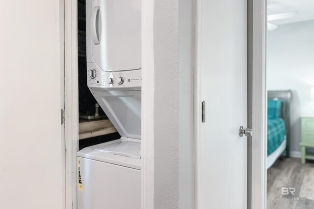 washroom with stacked washer and clothes dryer and hardwood / wood-style floors