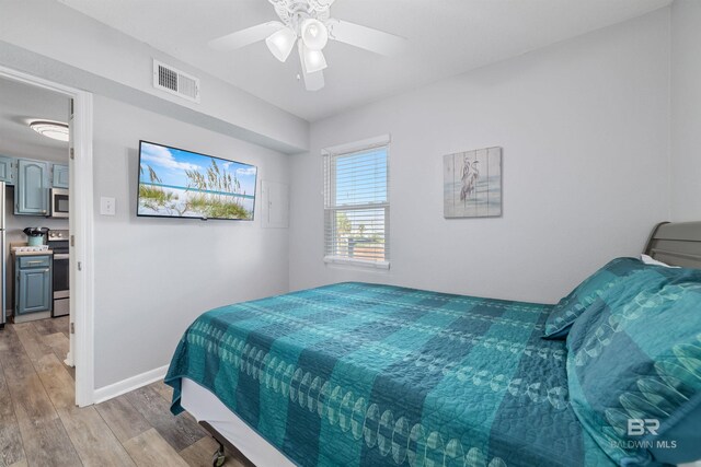 bedroom featuring ceiling fan, light wood-type flooring, and stainless steel fridge