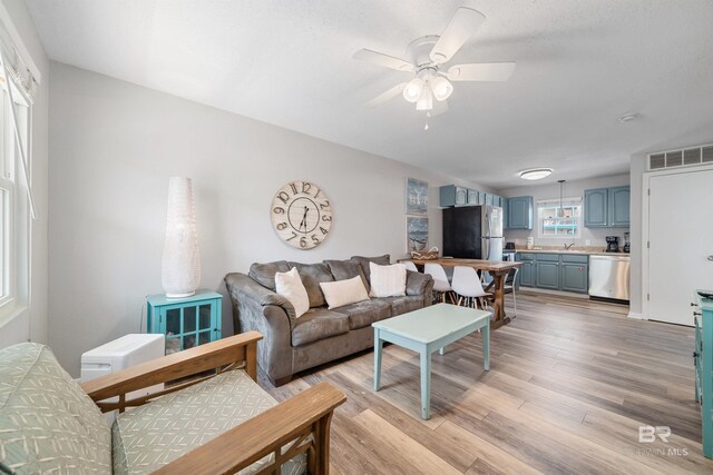 living room featuring light wood-type flooring, ceiling fan, and sink