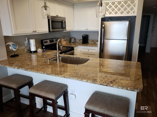 kitchen featuring white cabinets, a peninsula, stainless steel appliances, and light stone countertops