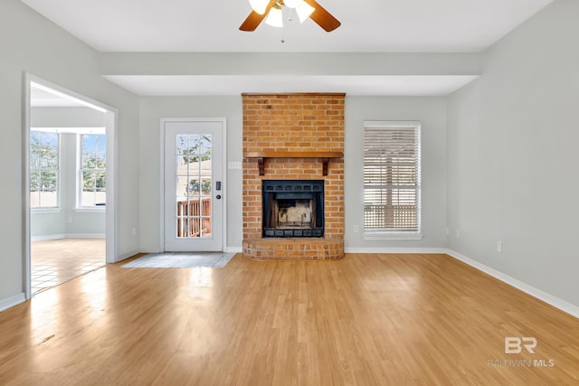 unfurnished living room featuring ceiling fan, baseboards, wood finished floors, and a fireplace