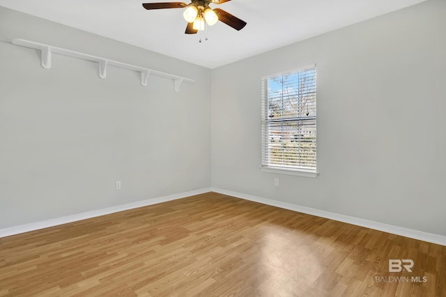 unfurnished room with a ceiling fan, baseboards, and light wood-type flooring