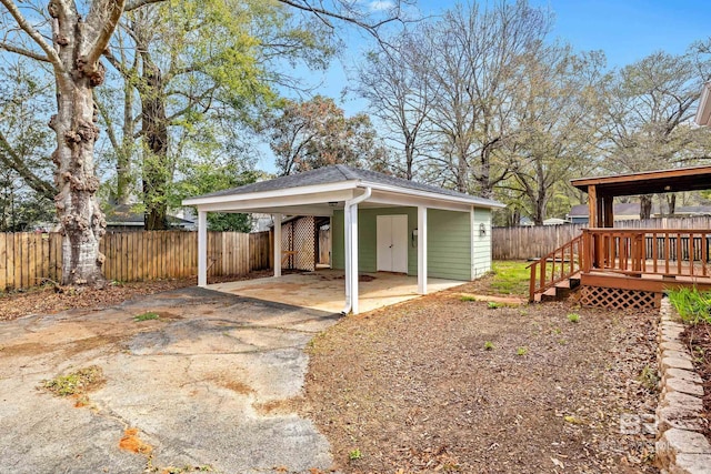 view of outbuilding with an attached carport, fence, and driveway