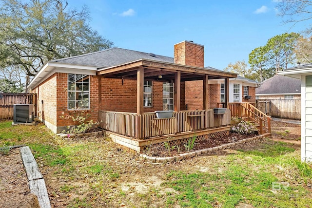 back of house featuring cooling unit, brick siding, a chimney, and fence