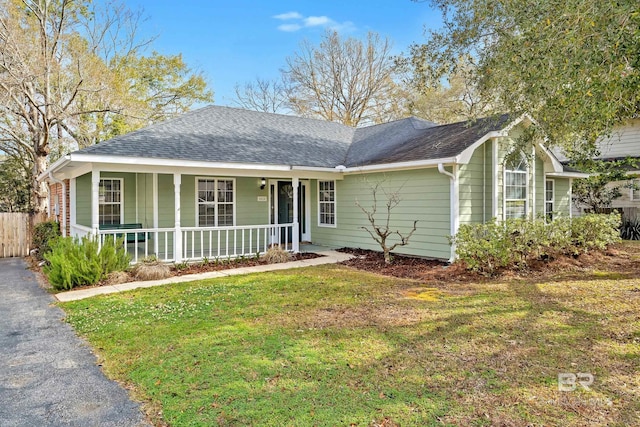 ranch-style house with fence, covered porch, a shingled roof, a front lawn, and aphalt driveway