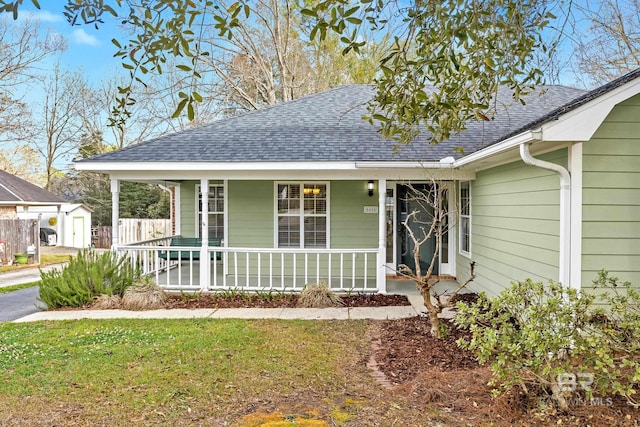 view of front of house with a front lawn, fence, covered porch, and roof with shingles