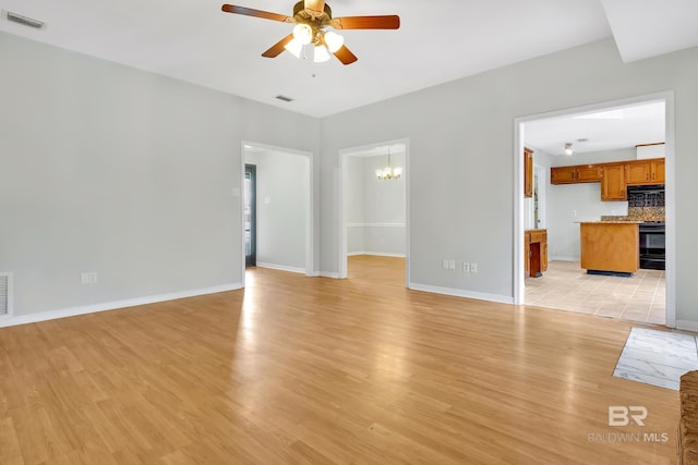 unfurnished living room featuring visible vents, light wood finished floors, baseboards, and ceiling fan with notable chandelier