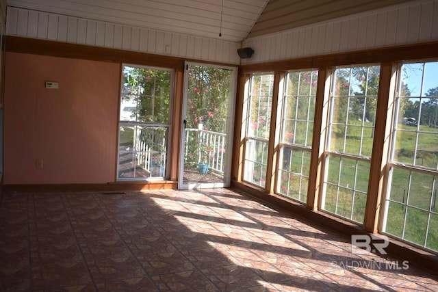 unfurnished sunroom featuring a wealth of natural light and vaulted ceiling