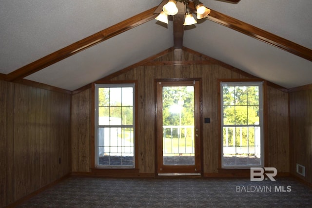 bonus room with lofted ceiling with beams, a healthy amount of sunlight, and wood walls