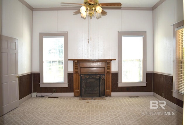 unfurnished living room with crown molding, wooden walls, and ceiling fan