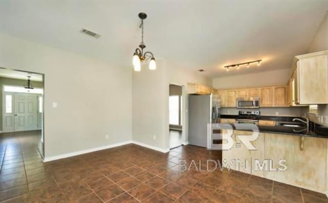 kitchen featuring kitchen peninsula, stainless steel appliances, dark tile patterned flooring, and track lighting