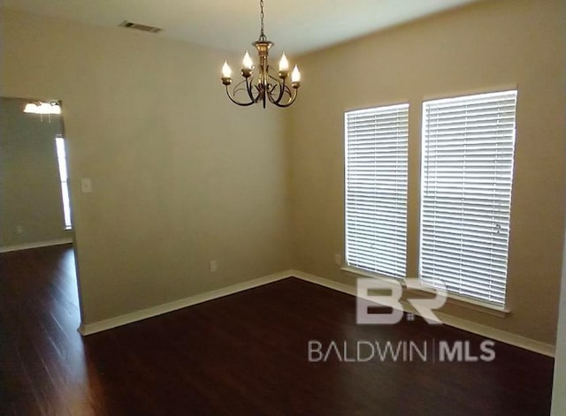 unfurnished room featuring a notable chandelier and dark wood-type flooring